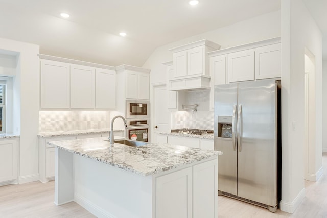 kitchen featuring sink, lofted ceiling, a center island with sink, white cabinets, and appliances with stainless steel finishes