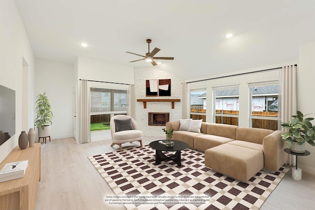 living room featuring a stone fireplace, ceiling fan, light hardwood / wood-style floors, and lofted ceiling