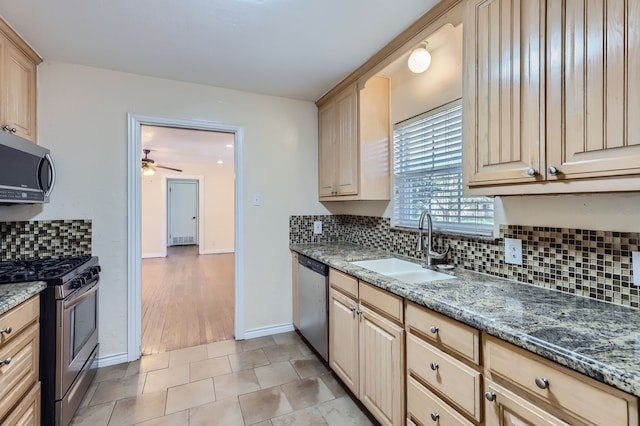 kitchen with stainless steel appliances, sink, stone counters, and light brown cabinetry