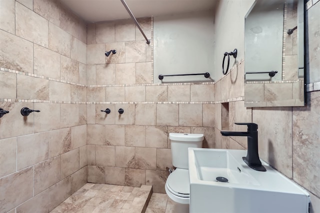 bathroom featuring sink, a tile shower, and toilet