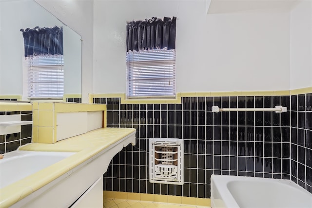 bathroom with vanity, tile walls, and a bathtub