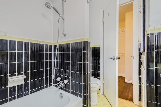 bathroom with tile walls, tile patterned floors, shower / bathtub combination, and toilet