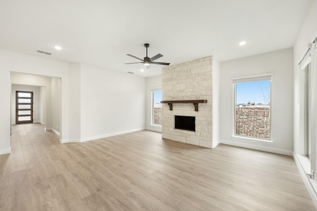 unfurnished living room with plenty of natural light, a fireplace, and light hardwood / wood-style floors