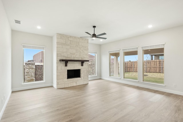 unfurnished living room featuring a stone fireplace, light hardwood / wood-style floors, and ceiling fan