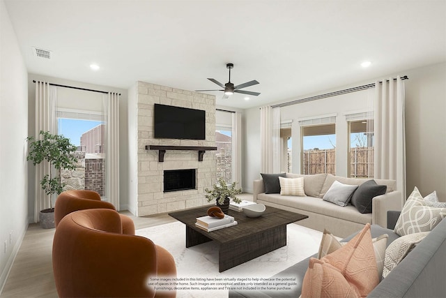 living room featuring a fireplace, light hardwood / wood-style floors, ceiling fan, and plenty of natural light