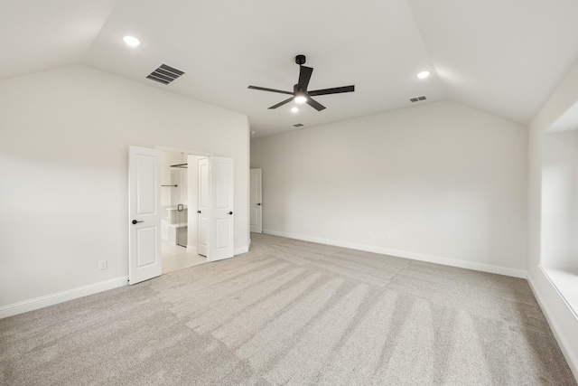 unfurnished bedroom with connected bathroom, vaulted ceiling, light colored carpet, and ceiling fan