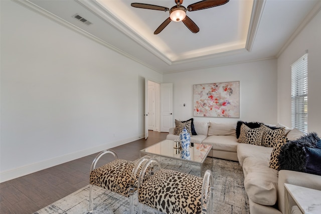 living room featuring ceiling fan, a raised ceiling, dark hardwood / wood-style floors, and crown molding