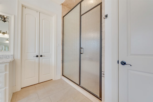 bathroom with tile patterned flooring, a shower with door, and vanity