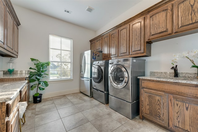 laundry area featuring washing machine and clothes dryer, sink, light tile patterned floors, and cabinets