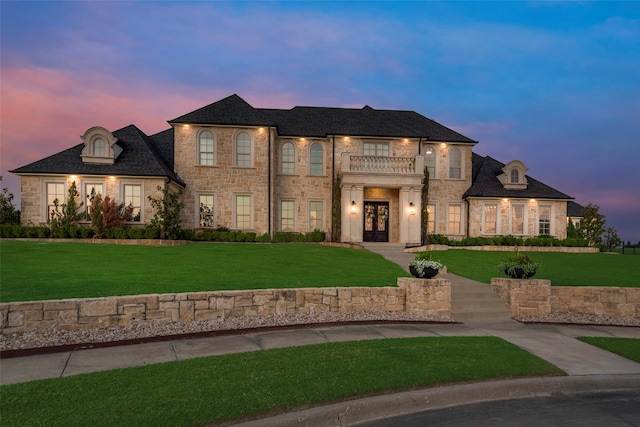 french country inspired facade featuring a balcony and a lawn