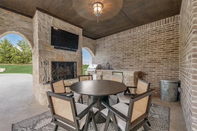 view of patio / terrace featuring an outdoor stone fireplace, sink, grilling area, and exterior kitchen