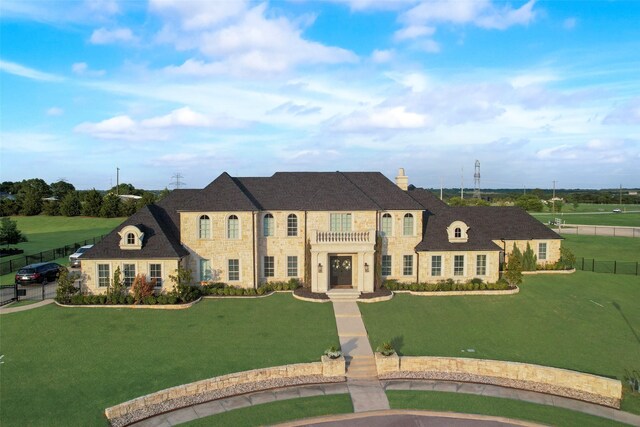 french provincial home with fence, a chimney, a front lawn, and stone siding