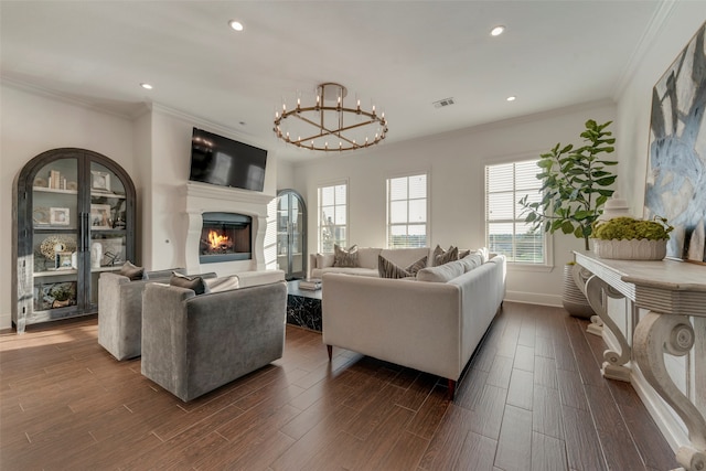 living room featuring ornamental molding, a notable chandelier, and dark wood-type flooring