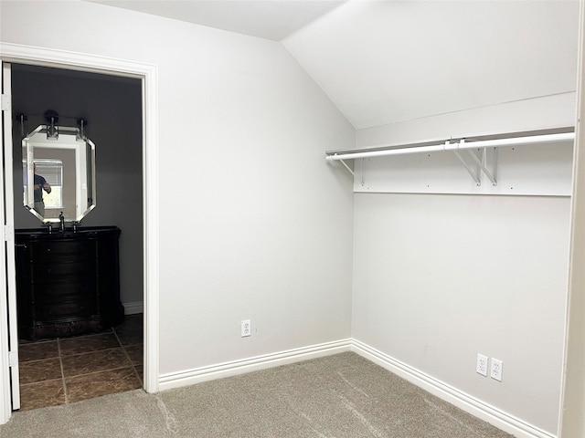 spacious closet with vaulted ceiling and dark colored carpet