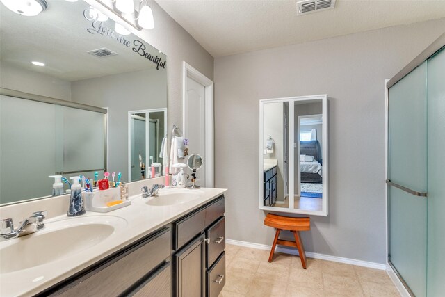 bathroom featuring walk in shower, vanity, a textured ceiling, and tile patterned floors