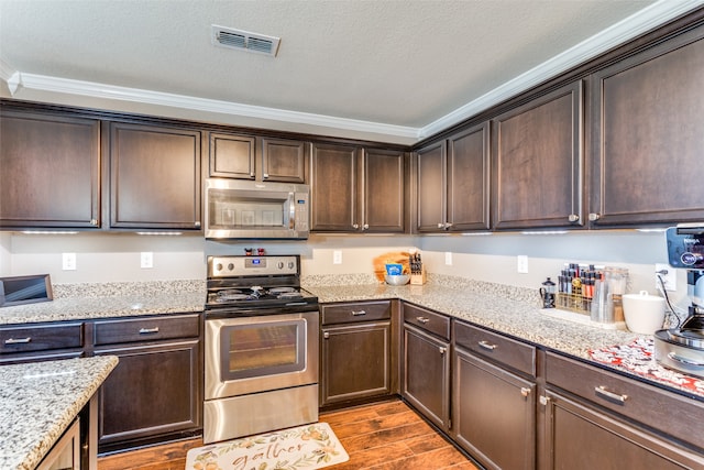 kitchen featuring dark hardwood / wood-style flooring, light stone countertops, ornamental molding, and stainless steel appliances