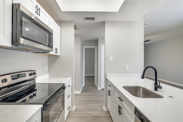 kitchen featuring visible vents, appliances with stainless steel finishes, white cabinets, and a sink