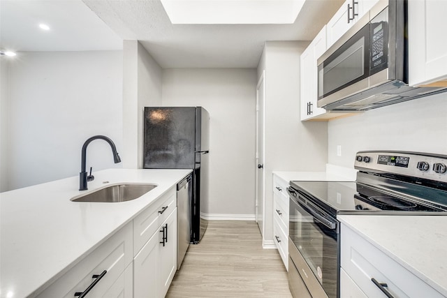 kitchen featuring white cabinetry, stainless steel appliances, sink, and light hardwood / wood-style flooring