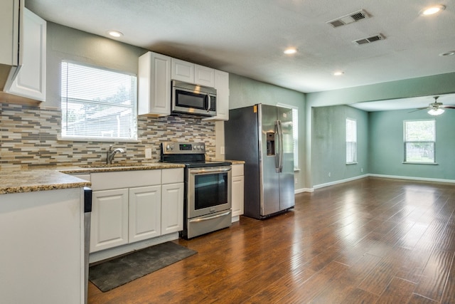 kitchen with white cabinets, stainless steel appliances, a healthy amount of sunlight, and dark hardwood / wood-style flooring