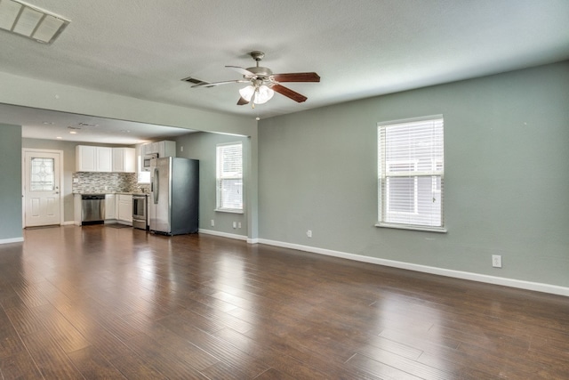 unfurnished living room featuring a wealth of natural light and dark hardwood / wood-style floors