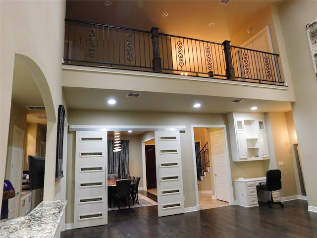 living room with wood-type flooring and a towering ceiling