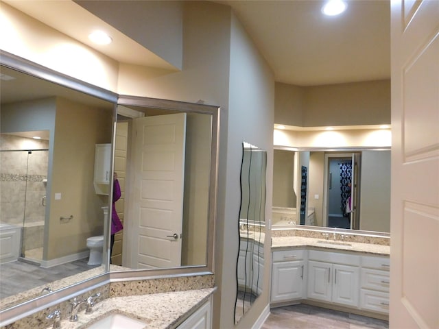 bathroom with a sink, a stall shower, toilet, and two vanities