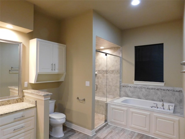 full bathroom with a stall shower, toilet, vanity, a garden tub, and wood finished floors