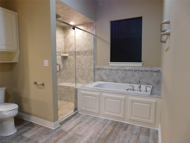 bathroom with a shower stall, wood finished floors, toilet, and a bath