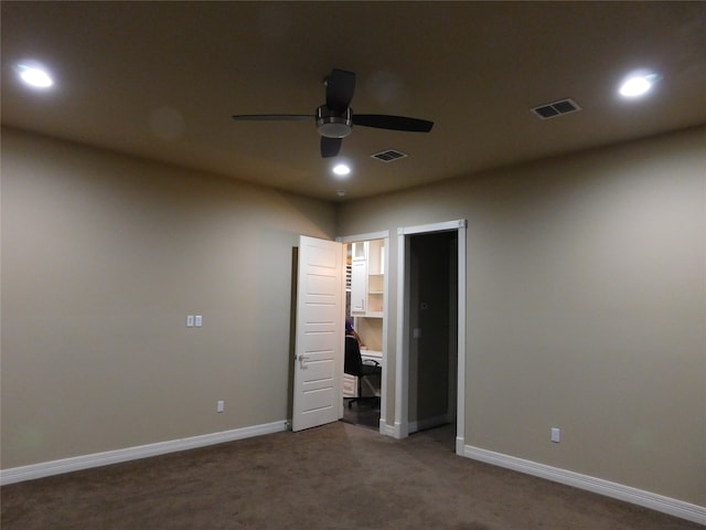 unfurnished bedroom with a spacious closet, dark carpet, and ceiling fan