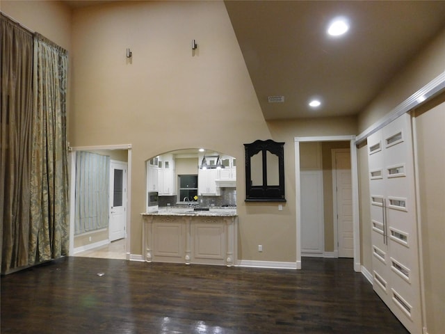 kitchen with dark wood-style flooring, white cabinets, visible vents, recessed lighting, and arched walkways