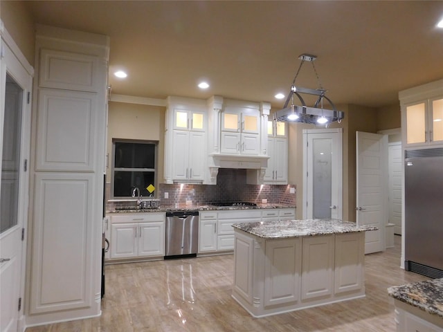 kitchen featuring a center island, appliances with stainless steel finishes, glass insert cabinets, white cabinetry, and backsplash