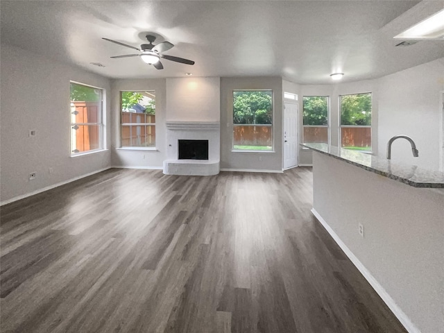 unfurnished living room with ceiling fan, a healthy amount of sunlight, dark hardwood / wood-style flooring, and sink