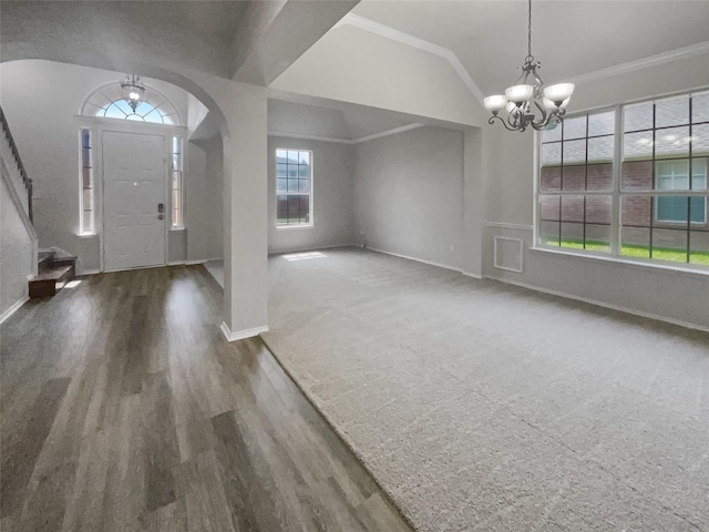 foyer entrance featuring crown molding, dark colored carpet, vaulted ceiling, and an inviting chandelier