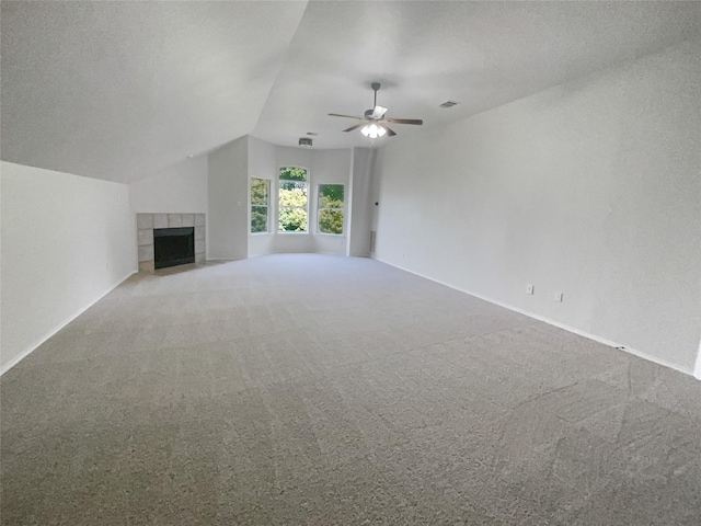 unfurnished living room featuring a textured ceiling, vaulted ceiling, ceiling fan, a tile fireplace, and carpet floors