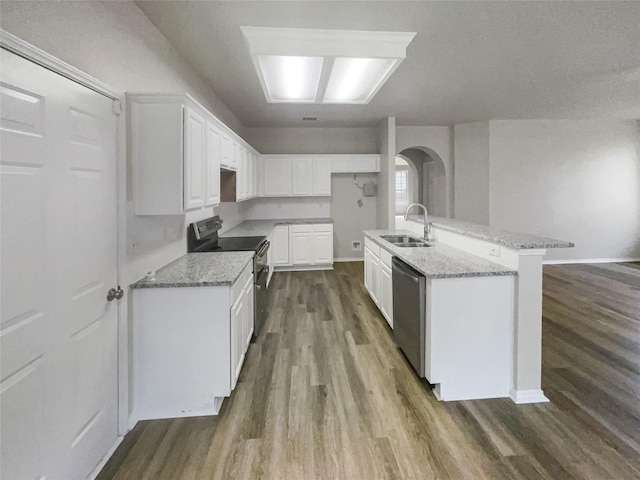 kitchen with a center island with sink, sink, light stone countertops, white cabinetry, and stainless steel appliances