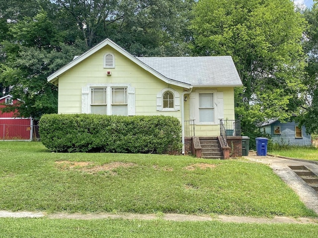 bungalow-style home featuring roof with shingles and a front lawn