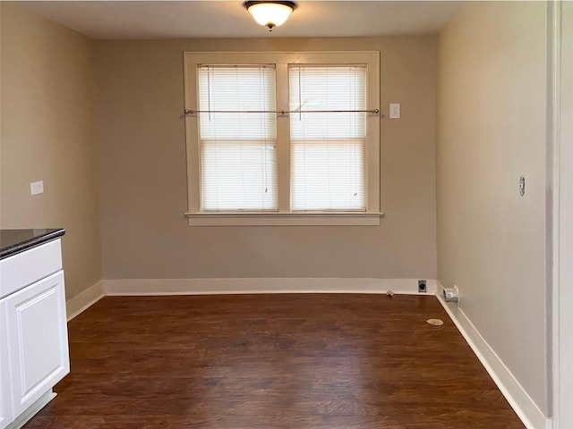 unfurnished dining area with a wealth of natural light, baseboards, and dark wood finished floors