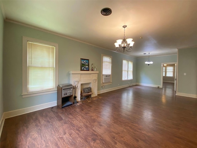 unfurnished living room with an inviting chandelier, a brick fireplace, crown molding, and dark hardwood / wood-style floors