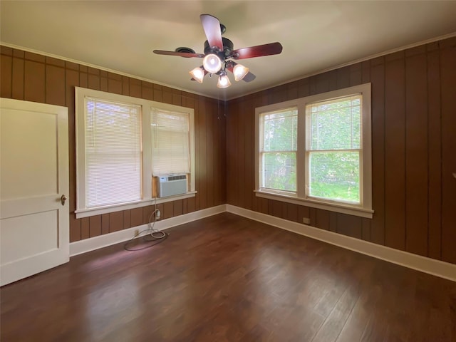 spare room featuring cooling unit, wooden walls, dark wood-type flooring, and ceiling fan