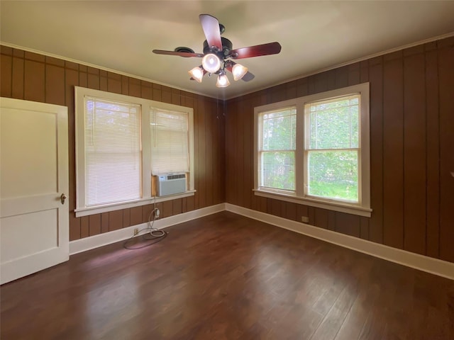 spare room featuring dark wood-type flooring, baseboards, crown molding, cooling unit, and a ceiling fan