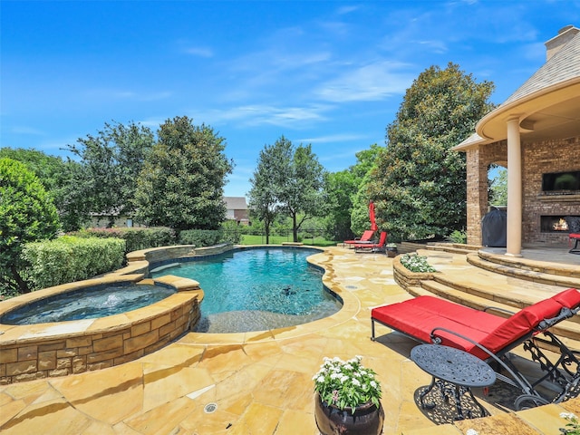 view of pool featuring exterior fireplace, a patio, and an in ground hot tub