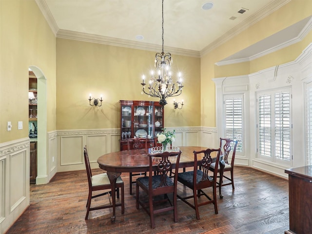 dining area featuring dark wood-type flooring, crown molding, and an inviting chandelier