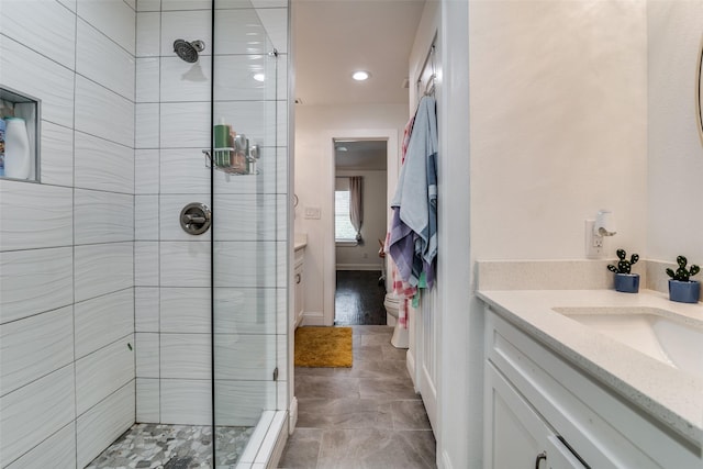 bathroom with a stall shower, vanity, and baseboards