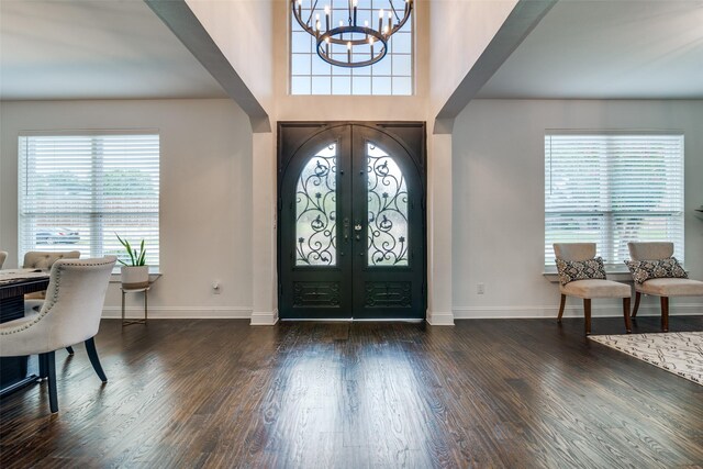 entrance foyer featuring an inviting chandelier, french doors, and dark wood-type flooring