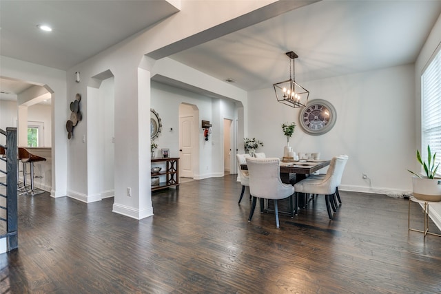 dining space featuring arched walkways, a notable chandelier, baseboards, and wood finished floors