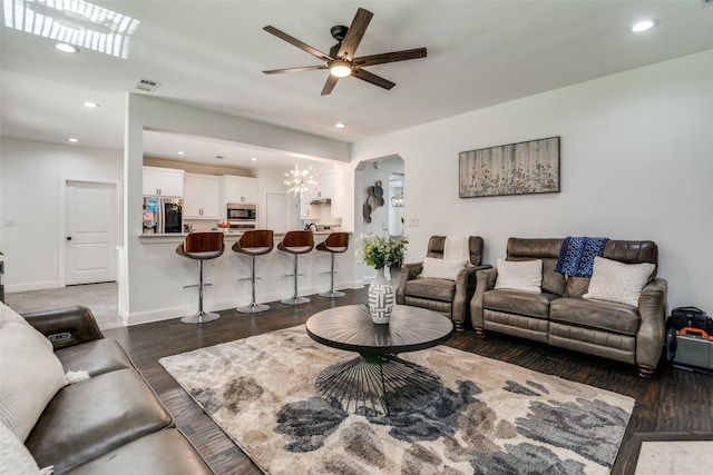 living area featuring visible vents, arched walkways, wood finished floors, ceiling fan with notable chandelier, and recessed lighting