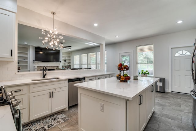 kitchen with a peninsula, a kitchen island, a sink, appliances with stainless steel finishes, and light stone countertops