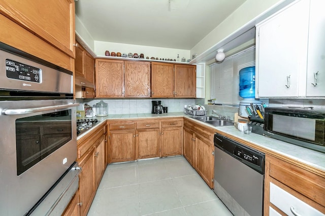 kitchen featuring light tile patterned flooring, sink, backsplash, tile counters, and stainless steel appliances