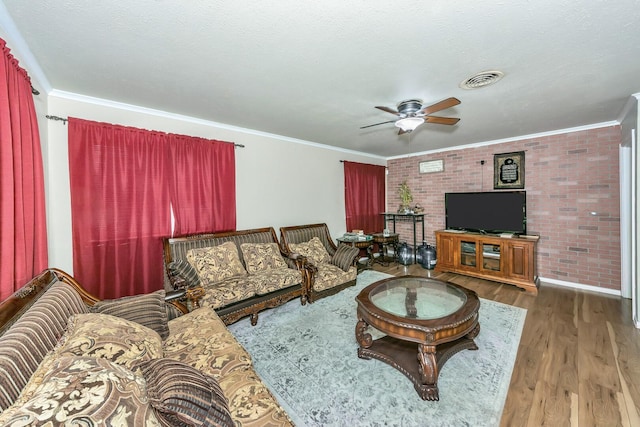 living room with wood-type flooring, ornamental molding, a textured ceiling, and brick wall