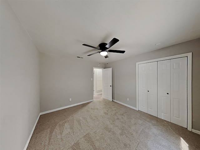 unfurnished bedroom featuring ceiling fan, a closet, and light colored carpet